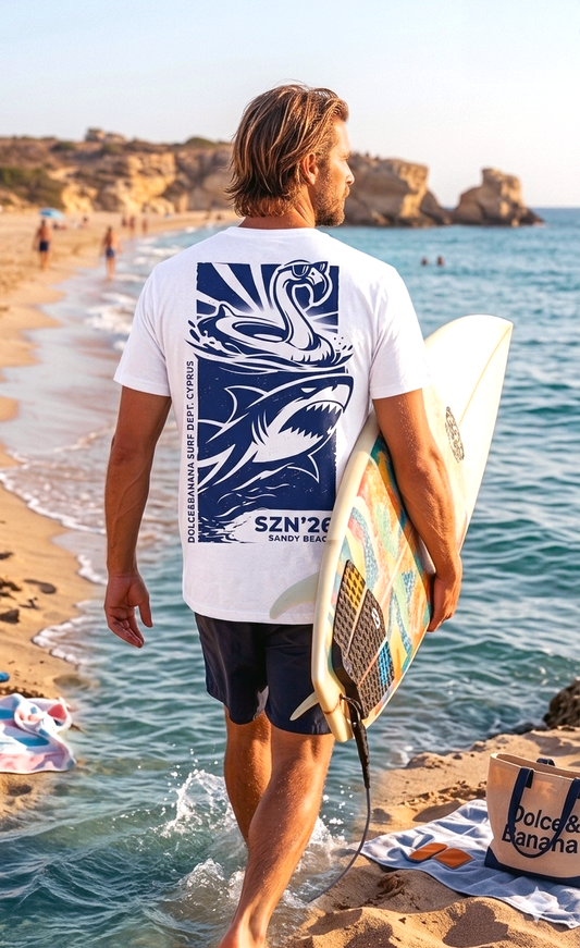 Male surfer walking into the sea at Sandy Beach Paphos wearing Dolce & Banana 2026 Surf Dept. white t-shirt with back print.